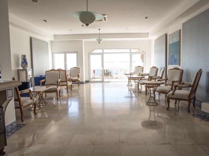 Jasna, elegancka przestrzeń wypoczynkowa z antycznymi fotelami i dużymi oknami z widokiem na taras.