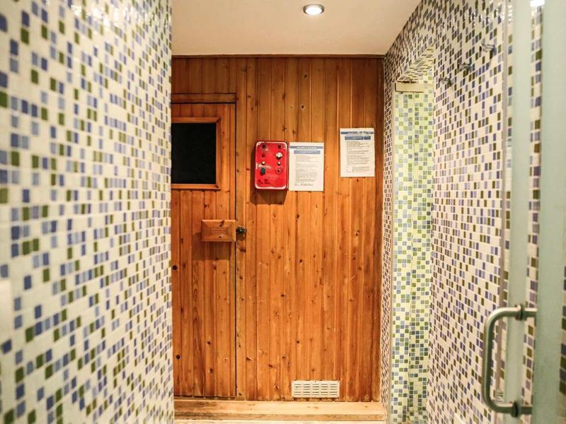 Pokój sauny z mozaikowymi ścianami i drewnianymi drzwiami w nowoczesnym hotelu