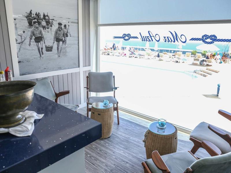 Jasny pokój hotelowy z balkonem, widokiem na morze i wygodnymi fotelami.