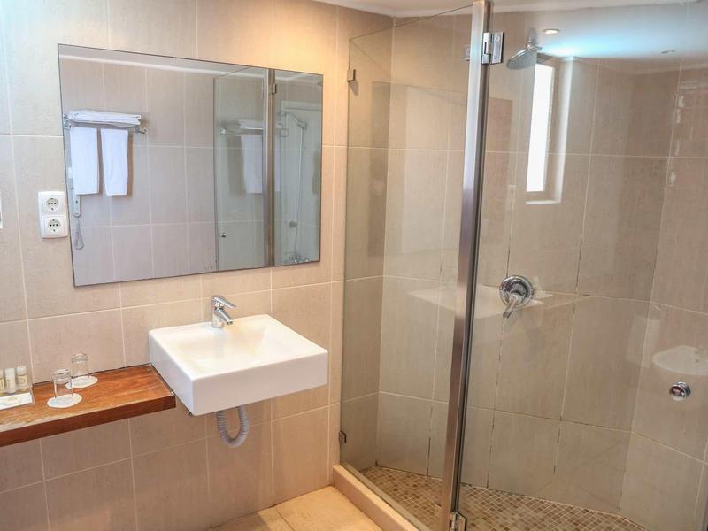 Nowoczesna łazienka z umywalką, dużym lustrem i szklaną kabiną prysznicową.