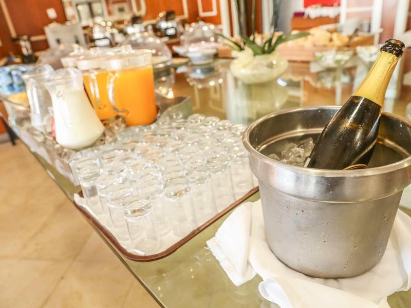 Orzeźwiające napoje, w tym butelka wina w kubełku z lodem i szklanki na stole.