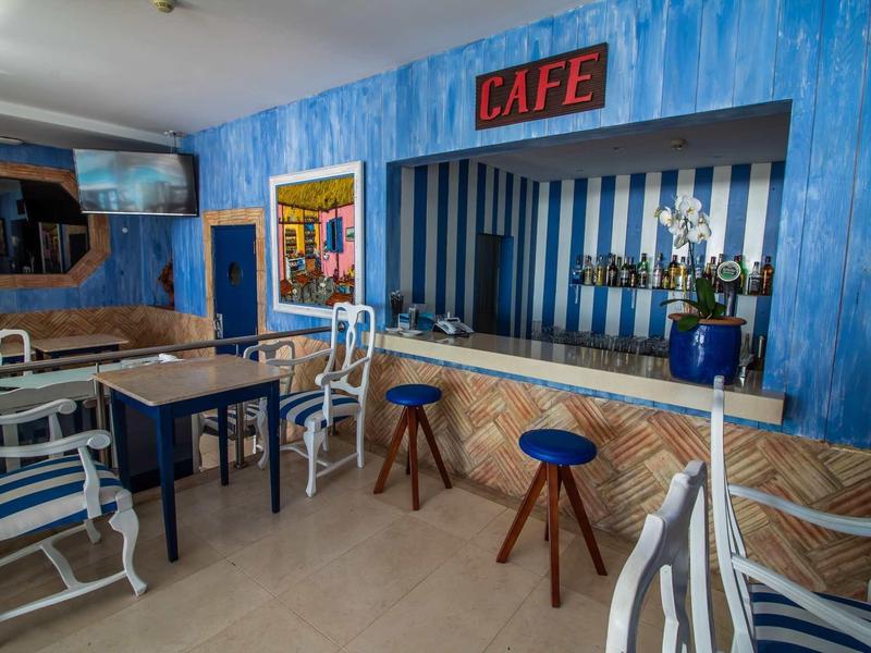 Przytulna kawiarnia w niebiesko-białych tonacjach, różne krzesła i lada z trofeami.