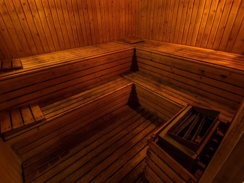 Przytulna sauna z drewnianą okładziną i wielopoziomowymi ławkami.