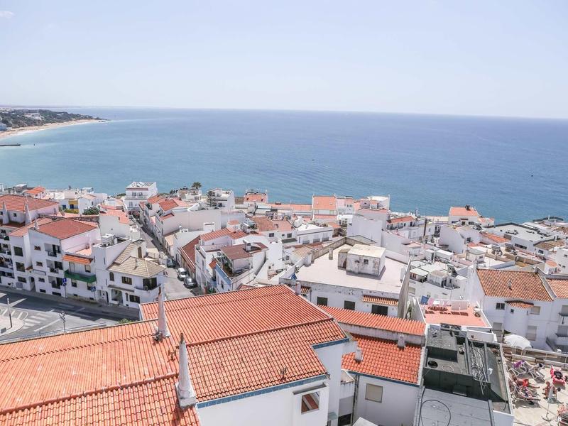 Widok na nadmiaste miasteczko z czerwonymi dachami i szerokim horyzontem morza pod czystym niebem.