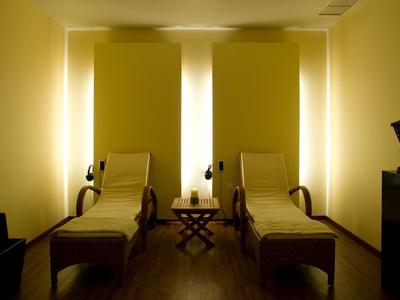 Tmavě osvětlená relaxační místnost s dvěma lehátky a nepřímým osvětlením.