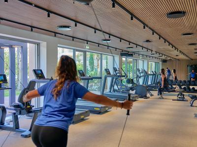 Innenansicht eines Fitnessstudios mit Trainingsgeräten und einer Person beim Training