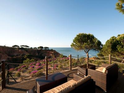 Terasa s posezením s výhledem na útesy a moře pod jasnou oblohou.