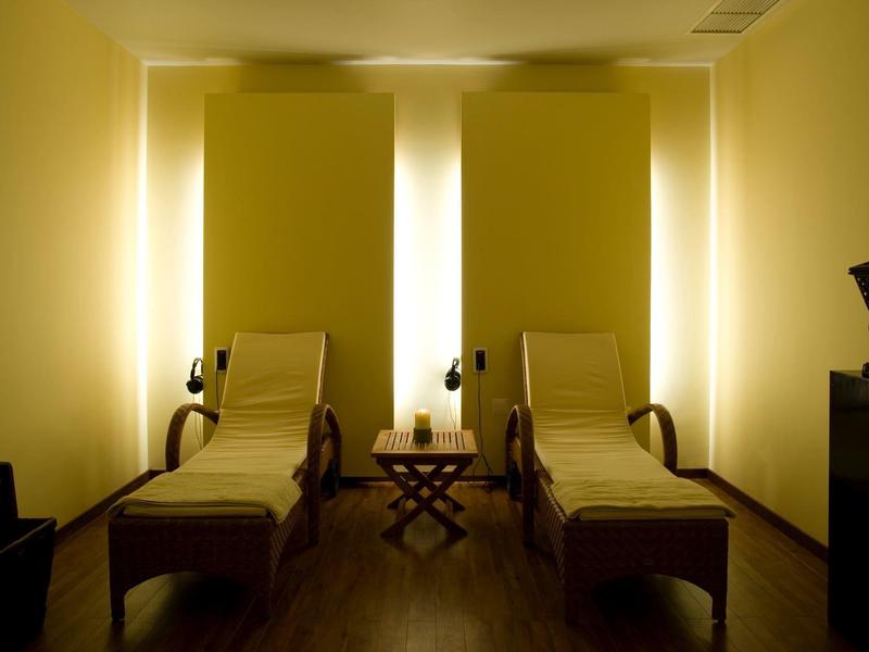 Tmavě osvětlená relaxační místnost s dvěma lehátky a nepřímým osvětlením.