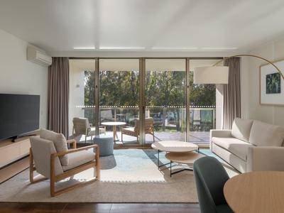 Sala luminosa con grandes ventanales y acceso a una terraza con asientos.