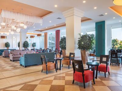 Geräumiger Hotellobbybereich mit Sitzgruppen, gemütlichen Sesseln und großen Fenstern.