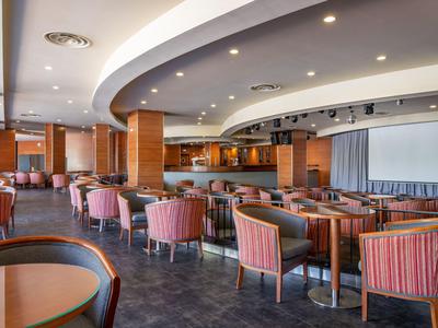 Großer, moderner Konferenzraum mit vielen Stuhlreihen und einem Präsentationsbildschirm.