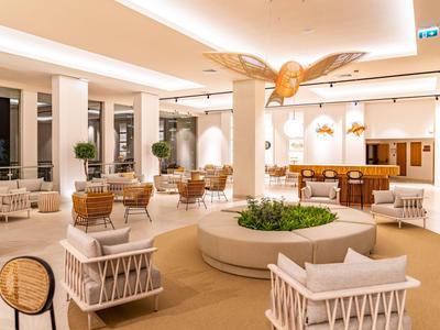 Heller Hotel-Loungebereich mit gemütlichen Sesseln und modernen Pflanzenarrangements.