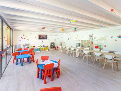 Lichte speelruimte voor kinderen met kleurrijke tafels en stoelen in een ruime kamer.