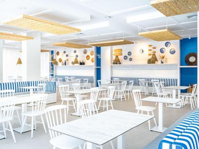 Helles, modernes Restaurant mit weißen Tischen, blauen Akzenten und Wanddekoration.