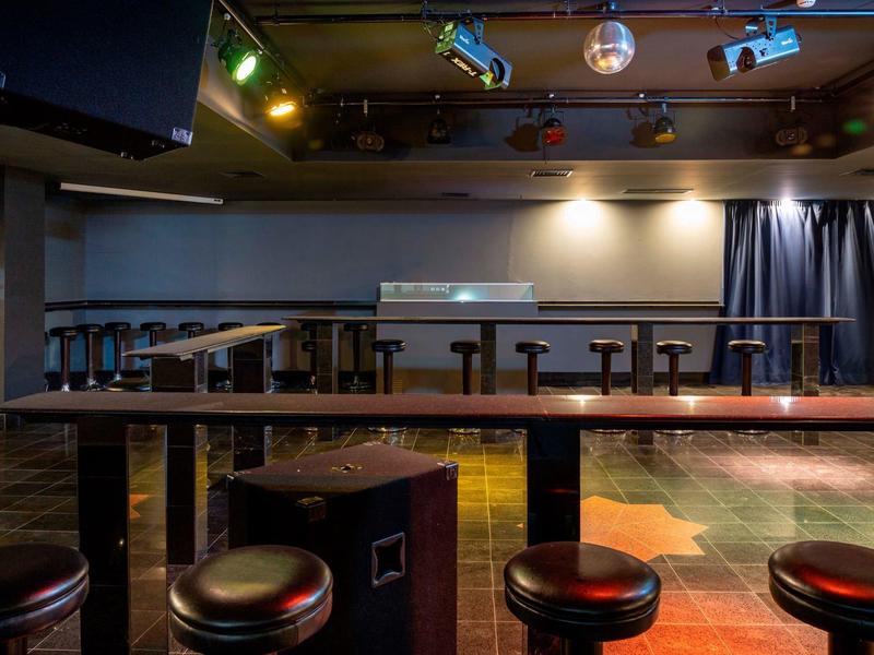 Leeg bargebied met krukken en gedimd, kleurrijk licht in een hotel lounge.