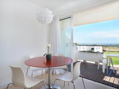 Heller Essbereich mit rundem Holztisch, vier weißen Stühlen und Blick auf Terrasse mit Sitzmöbeln und Garten.