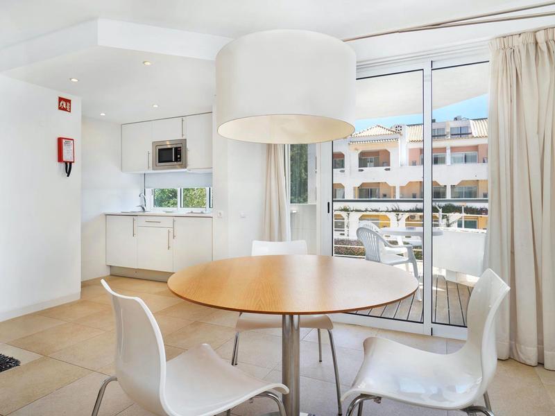 Heller Essbereich mit rundem Holztisch, weißen Stühlen und großer Pendelleuchte, angrenzend an Küche und Balkon.