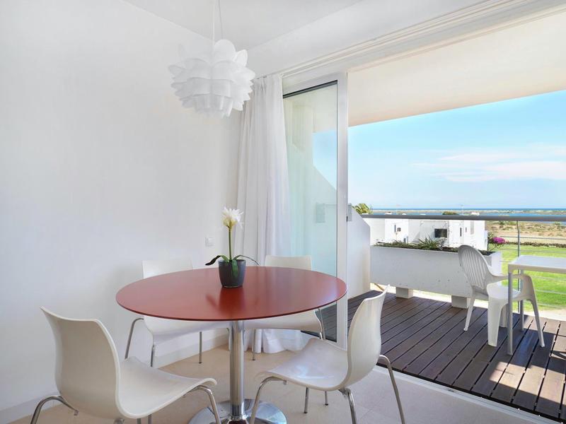 Heller Essbereich mit rundem Holztisch, vier weißen Stühlen und Blick auf Terrasse mit Sitzmöbeln und Garten.