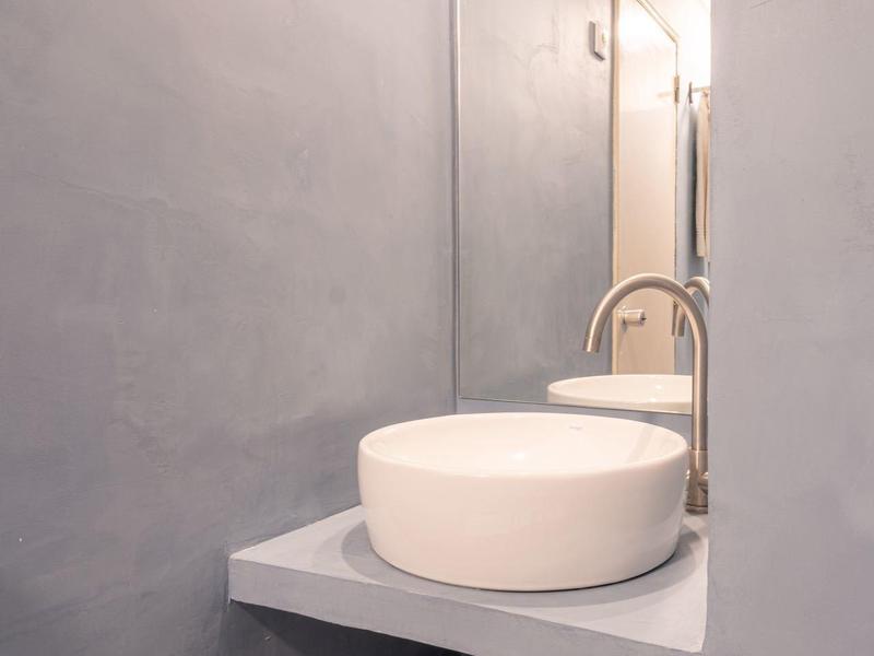 Modern washbasin with round sink and gray wall in bathroom.
