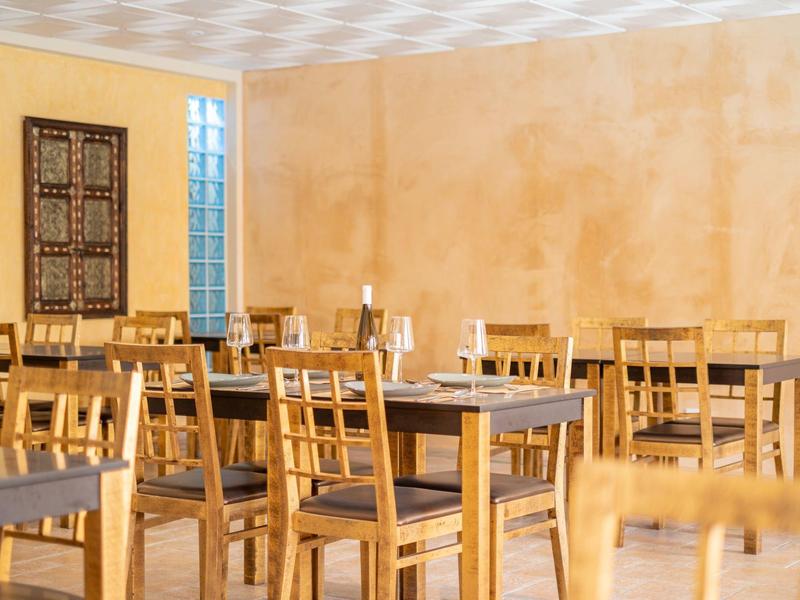 Empty dining room with wooden tables and chairs, yellow painted walls.