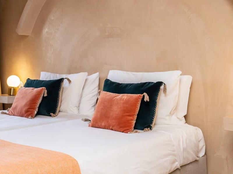 Cozy hotel room with white beds, colorful pillows, and warm lighting.