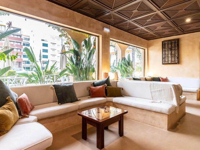 Bright living room with large windows, seating area, and wooden table in a hotel setting.