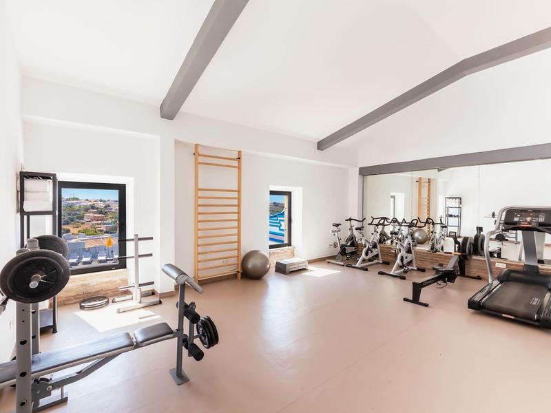 Lichte fitnessruimte met moderne trainingsapparatuur en ramen met uitzicht op zee.