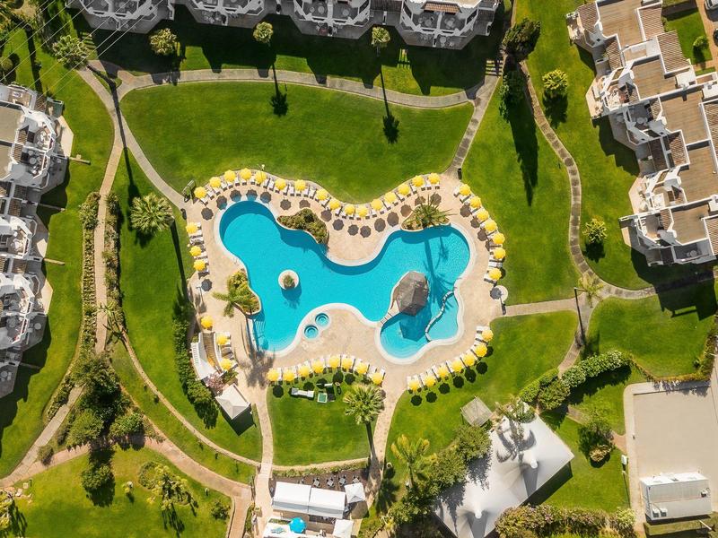 Luchtfoto van een hotel met een groot zwembad omgeven door groen gras