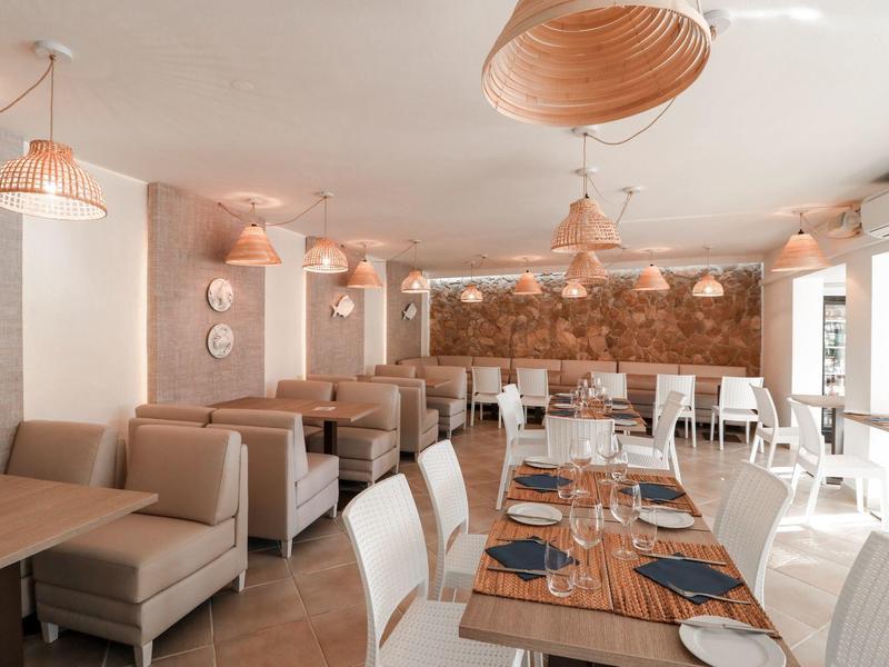 Modern restaurant met witte stoelen, houten tafels en warme verlichting.