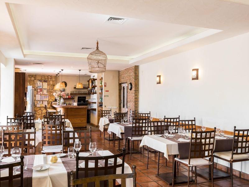 Licht restaurant met witte tafelkleden, donkere houten stoelen en een gezellige sfeer.