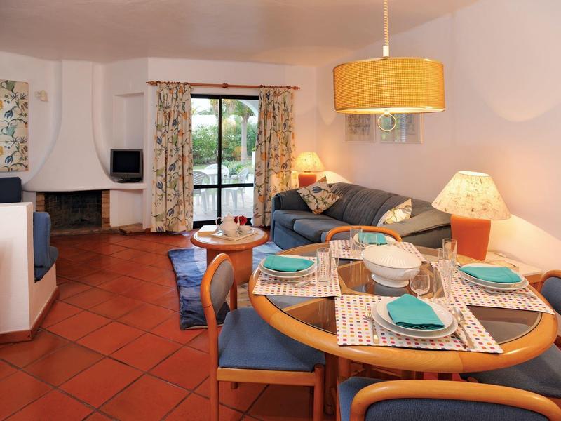 Gezellige woonkamer met eettafel, bank, open haard en toegang tot balkon.