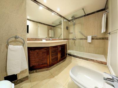 Nowoczesna łazienka z prysznicem, wanną, umywalką i dużymi lustrami.