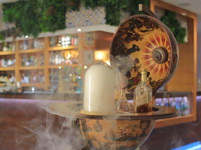 Bar z dekoracyjną butelką i podświetlonym okrągłym dziełem sztuki w tle