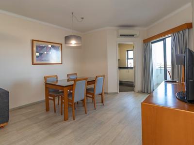 Nowoczesny salon z jadalnią, sofą, telewizorem i wyjściem na balkon.