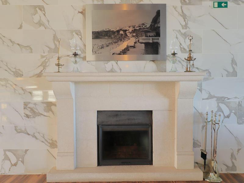 Nowoczesny kominek z jasnego marmuru z dekoracjami i drewnianą podłogą.