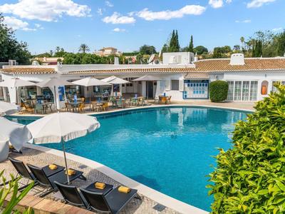 Rond hotelzwembad met ligstoelen en parasols in een mediterrane tuin