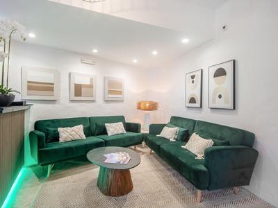 Moderne woonkamer met twee groene banken, een ronde houten tafel en wanddecoraties.