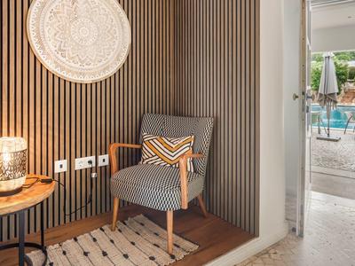 Gezellige leeshoek met gestreepte fauteuil, tafellamp en uitzicht op het zwembad.