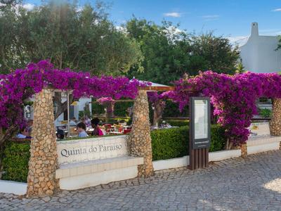 Buitengebied van een restaurant met stenen zuilen en weelderige paarse bloemen