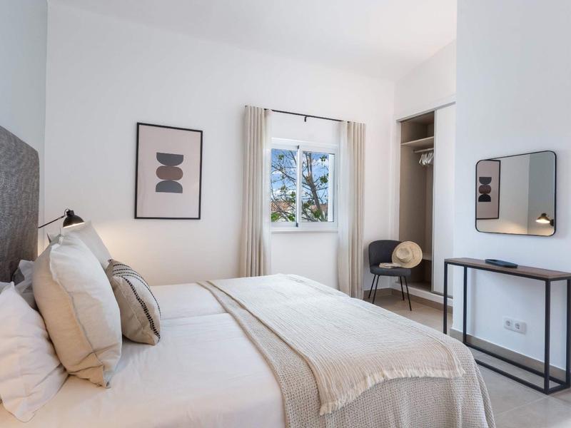 Lichte tweepersoonskamer met groot raam, neutrale inrichting en modern design.