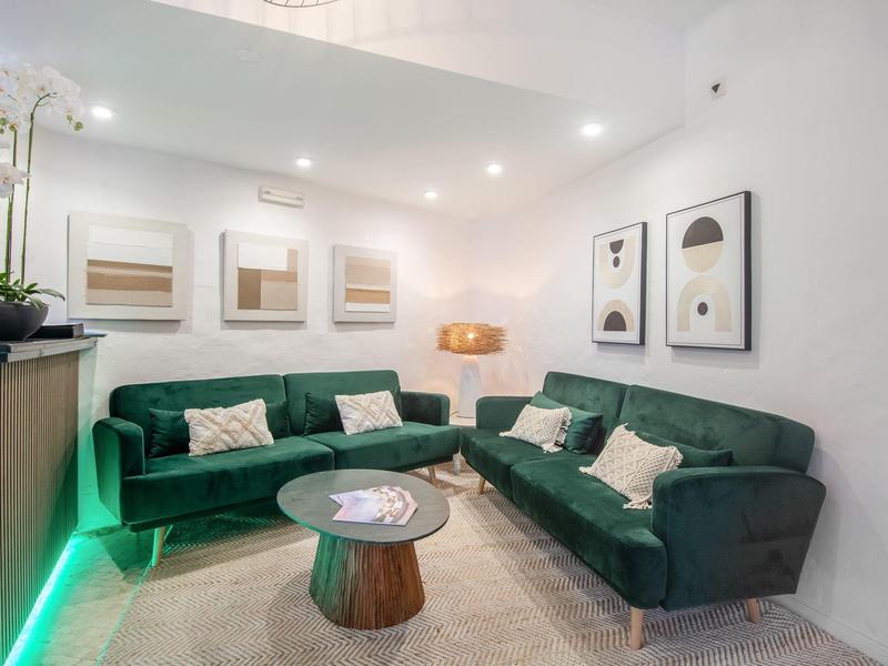 Moderne woonkamer met twee groene banken, een ronde houten tafel en wanddecoraties.