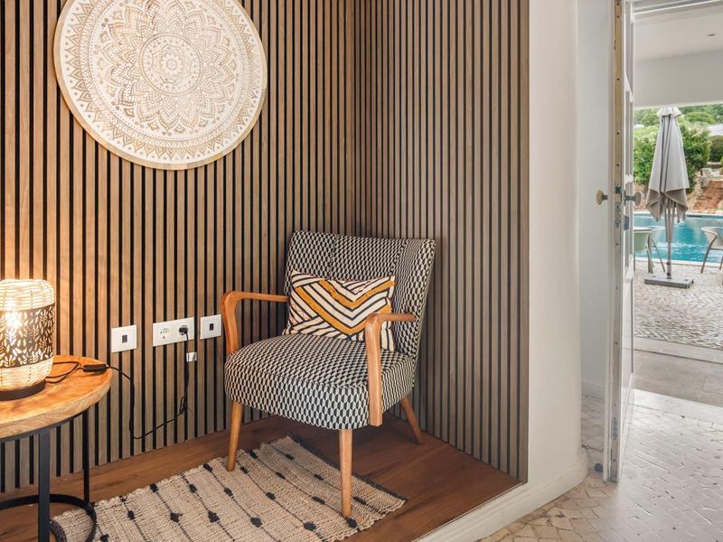 Gezellige leeshoek met gestreepte fauteuil, tafellamp en uitzicht op het zwembad.