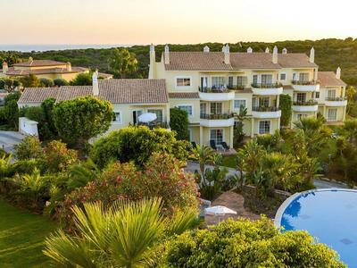 Kompleks hotelowy z basenem otoczony drzewami i otwartym krajobrazem o zachodzie słońca