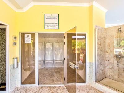 Wejście z żółtymi ścianami, szklanymi drzwiami obrotowymi i marmurową podłogą.