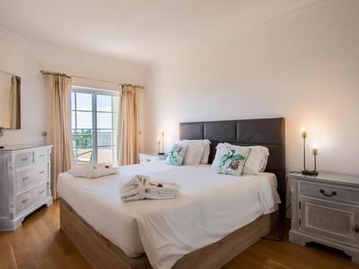 Helles Schlafzimmer mit Doppelbett, Nachttischen und Blick auf den Garten.