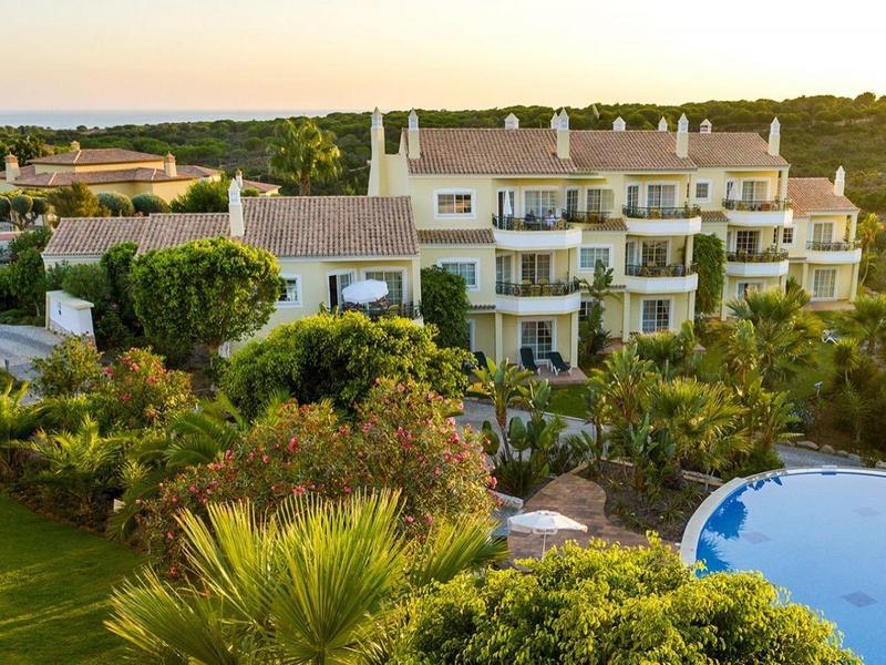 Kompleks hotelowy z basenem otoczony drzewami i otwartym krajobrazem o zachodzie słońca