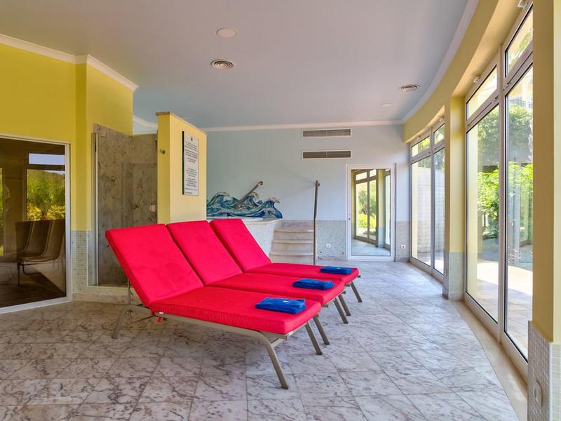 Jasnożółta strefa spa z różowymi leżakami i oknami od podłogi do sufitu