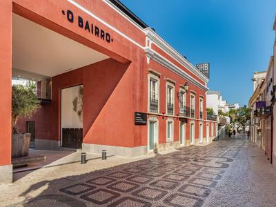 Cicha ulica z czerwonymi budynkami i wzorzystym chodnikiem pod jasnym, niebieskim niebem