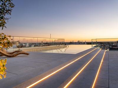 Nowoczesny basen na dachu z podświetlanymi schodami o zachodzie słońca