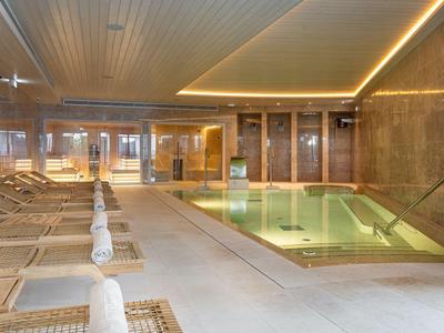 Nowoczesna strefa wellness z leżakami i podświetlanym basenem krytym w stylowym wnętrzu.